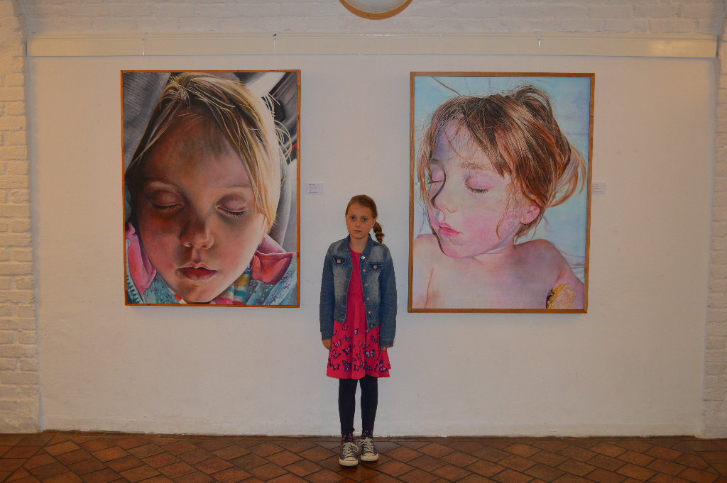 Phoebe in front of a couple of Phoebe paintings